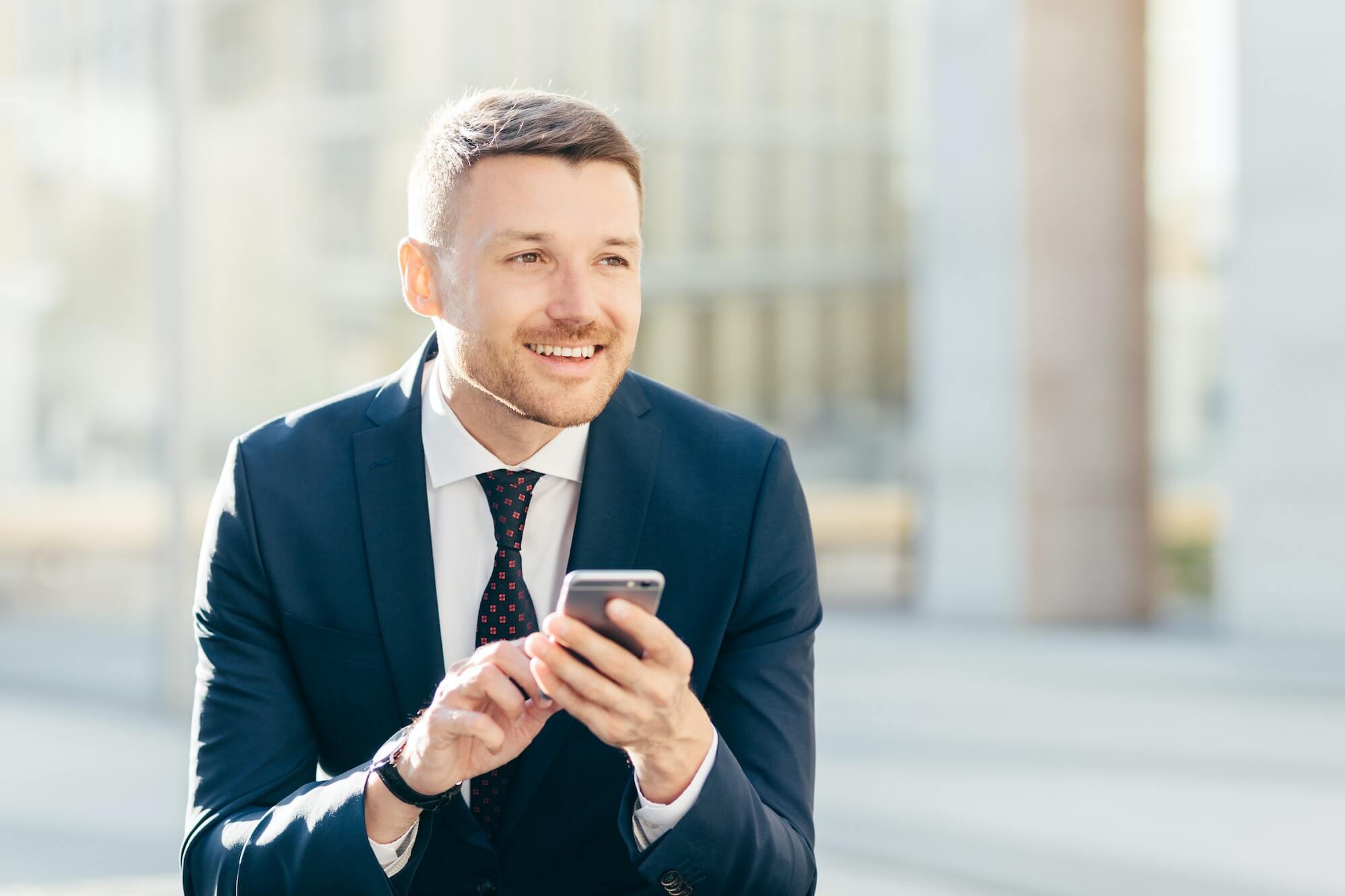 delighted thoughtful elegant male marketing trader in formal black suit uses modern cell phone1